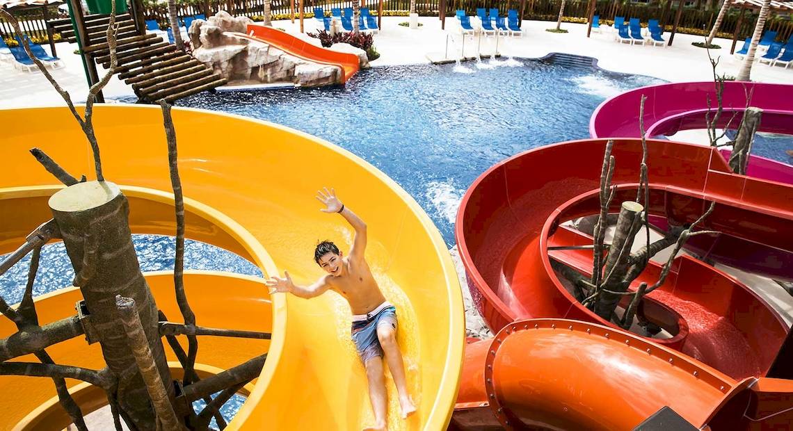 Ein Junge rutscht auf einer gelben Wasserrutsche im Wasserpark des Barcelo Maya Grand Resort.