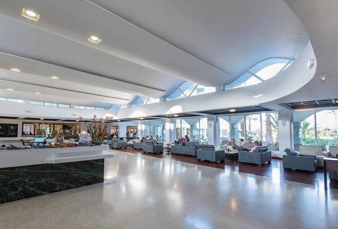 Lobby im Apollo Beach Hotel mit modernen Möbeln, hohen Decken und großen Fenstern.
