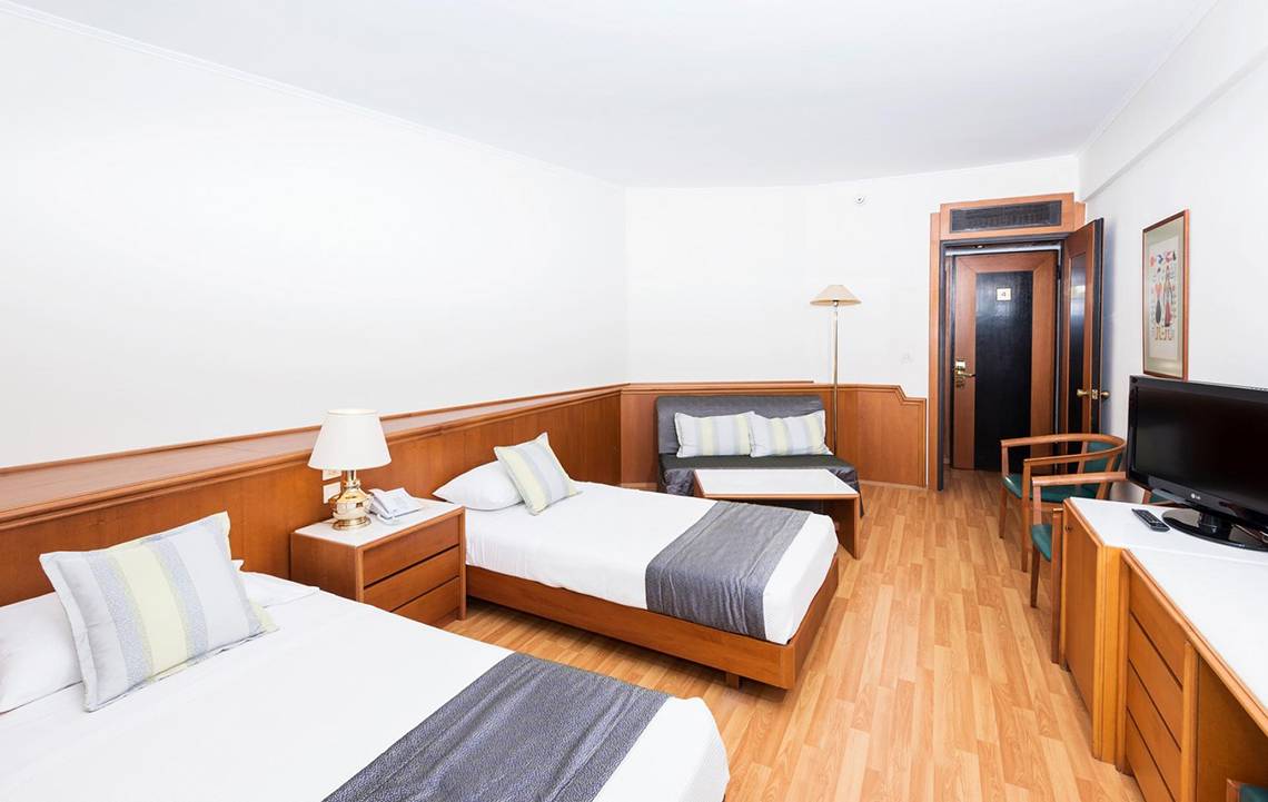 Doppelzimmer im Apollo Beach Hotel mit zwei Betten, Fernseher, Lampe und Couch