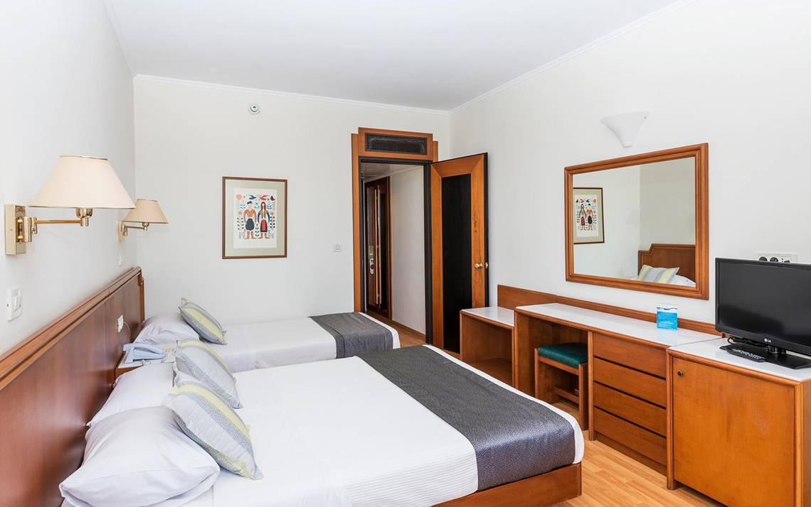 Doppelzimmer im Apollo Beach Hotel mit zwei Betten, Dekor, Spiegel und Fernseher.