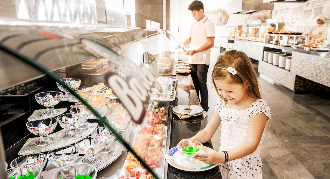Ein Kind genießt das Essen an einem Buffet im Barcelo Maya Grand Resort.