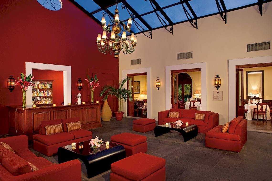 Roter Loungebereich im Dreams Tulum Resort & Spa mit roten Möbeln, zentralem Tisch und Bar im Hintergrund.