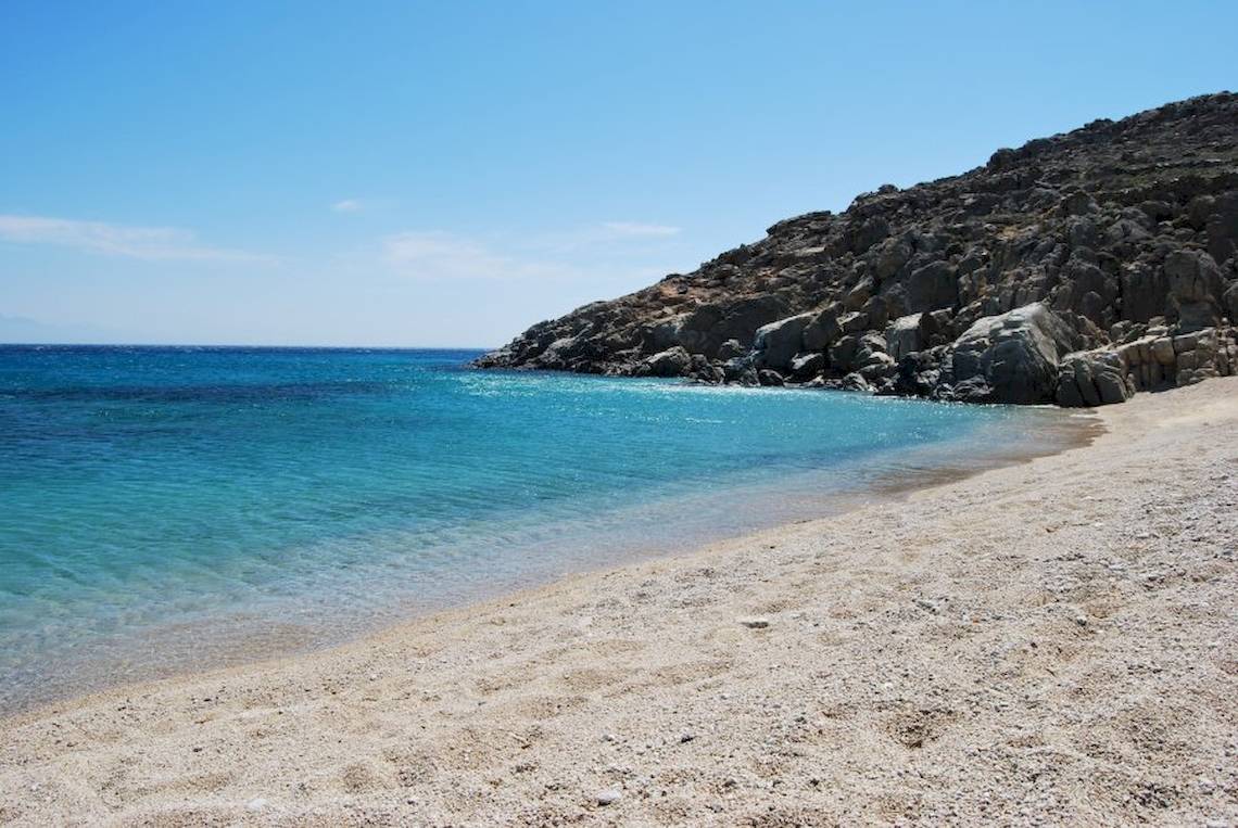 Strand mit felsigem Ufer und blauem Wasser unter einem blauen Himmel
