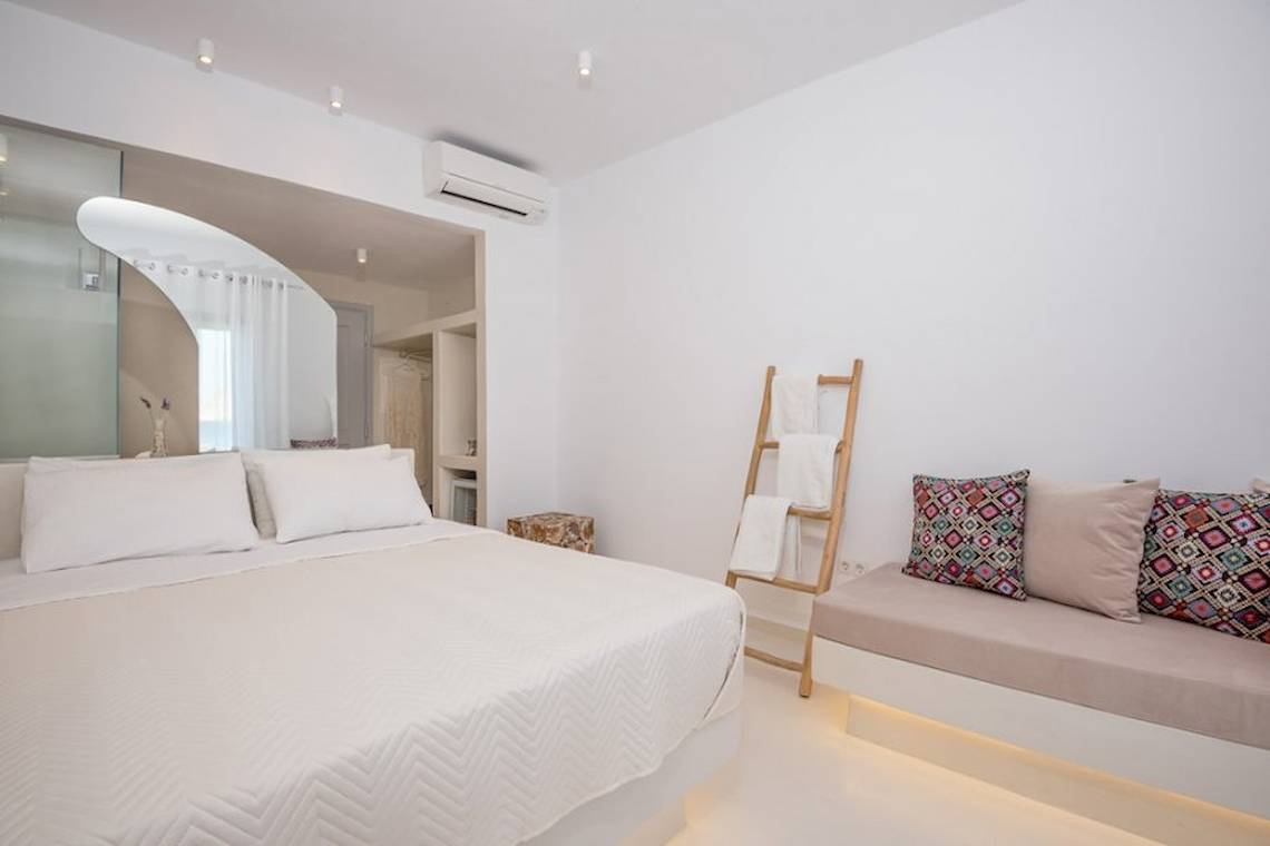 Schlafzimmer im Sunrise Mykonos Hotel mit Doppelbett, Kissen, und Sofa.