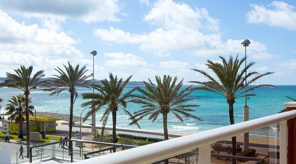 Aussicht von Universal Hotel Neptuno auf eine Palmenallee und den Strand.