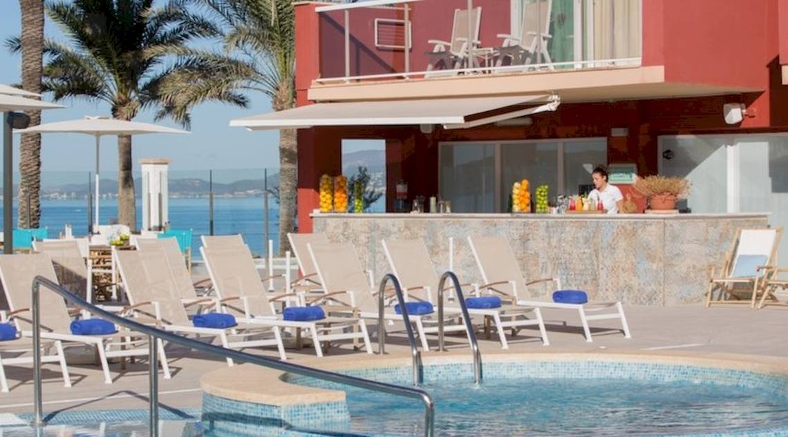 Poolbereich des Universal Hotel Neptuno mit Bar und Liegestühlen am Meer.