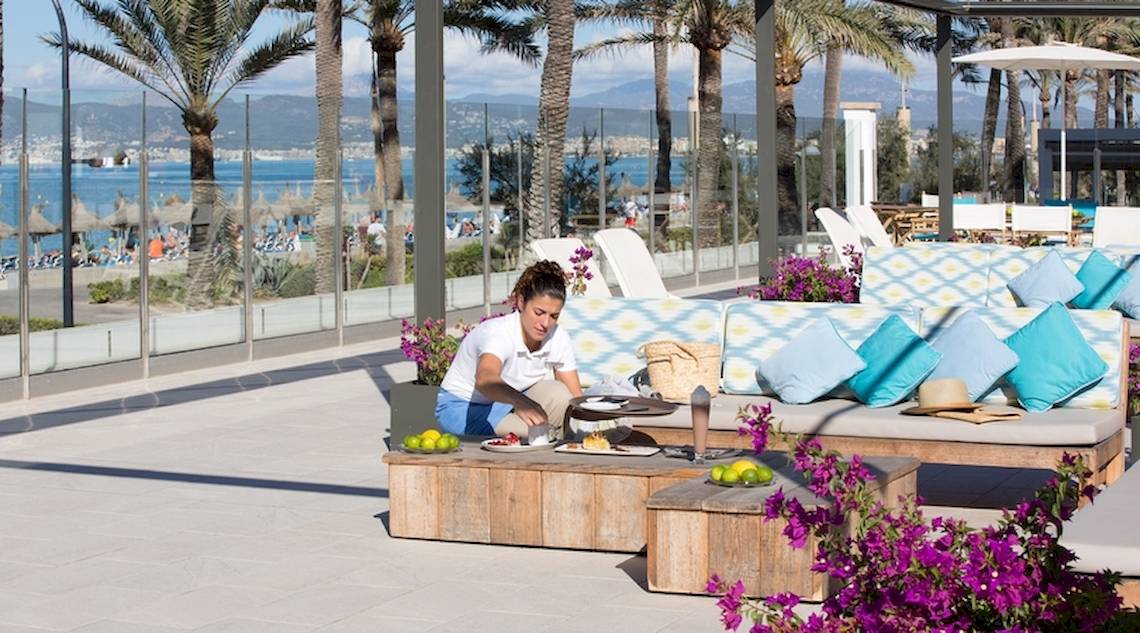 Ein Kellner serviert ein Essen auf der Terrasse des Universal Hotel Neptuno.