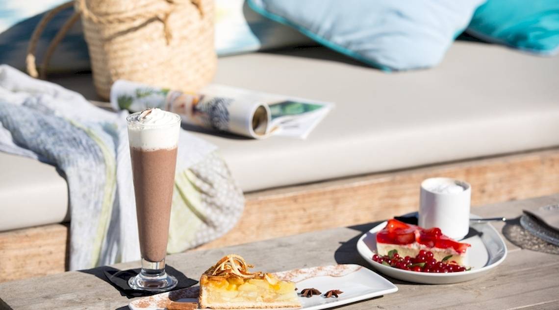 Frühstückstisch im Universal Hotel Neptuno mit Kuchen und Getränken auf einer Terrasse.