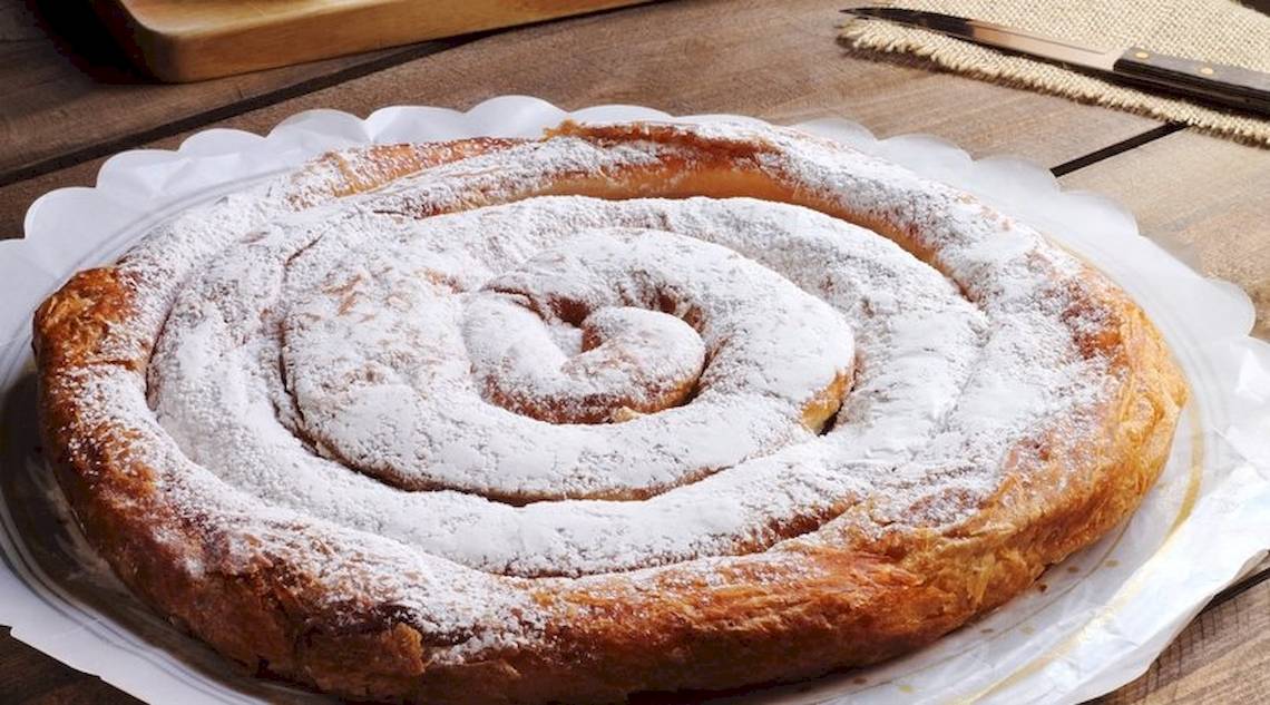 Ein Spiralgeburtstagskuchen mit Puderzucker bestreut auf einem weißen Teller.