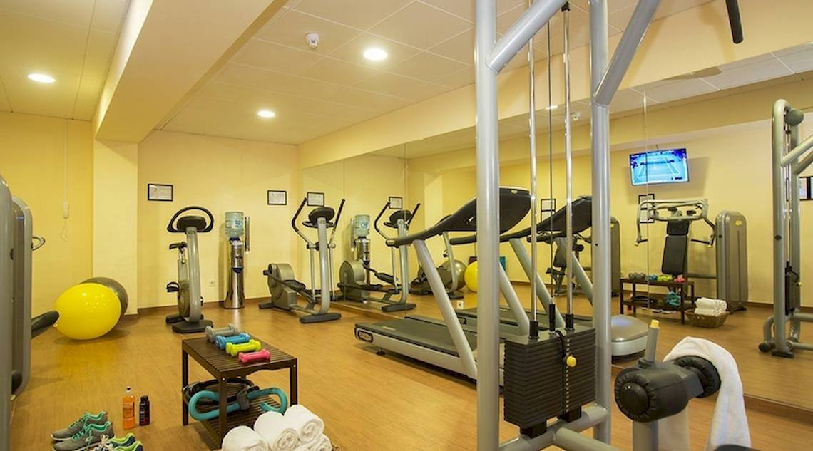 Fitnesscenter im Universal Hotel Neptuno mit Laufbändern, Hanteln und Trainingsgeräten.