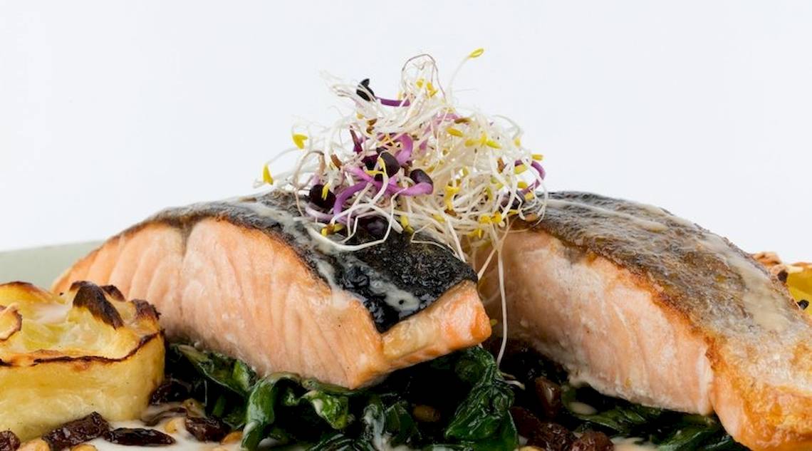 Ein Gericht mit Lachs, Spinat und Beilagen im Universal Hotel Neptuno.
