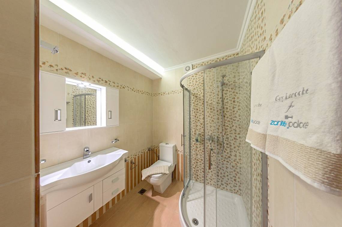 Ein Badezimmer im Zante Palace Hotel mit einer Dusche, Toilette und Waschbecken.