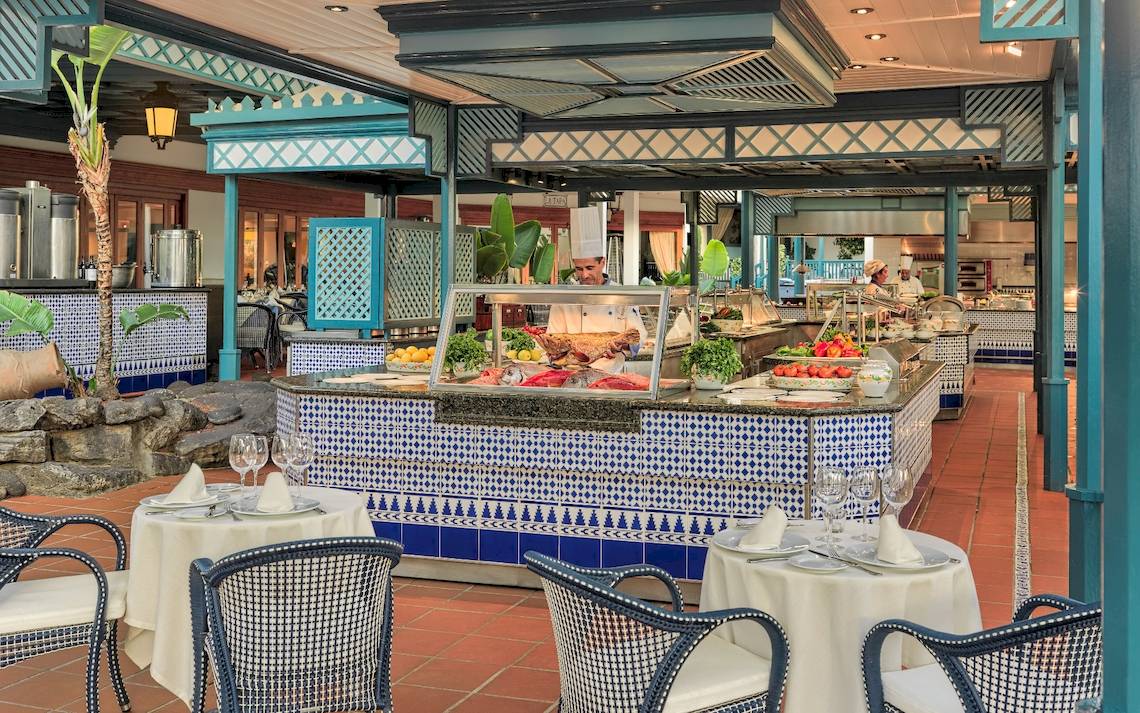 Innenansicht des Restaurants Seaside Los Jameos mit blau-weiß gefliester Theke, Tischen und Stühlen.