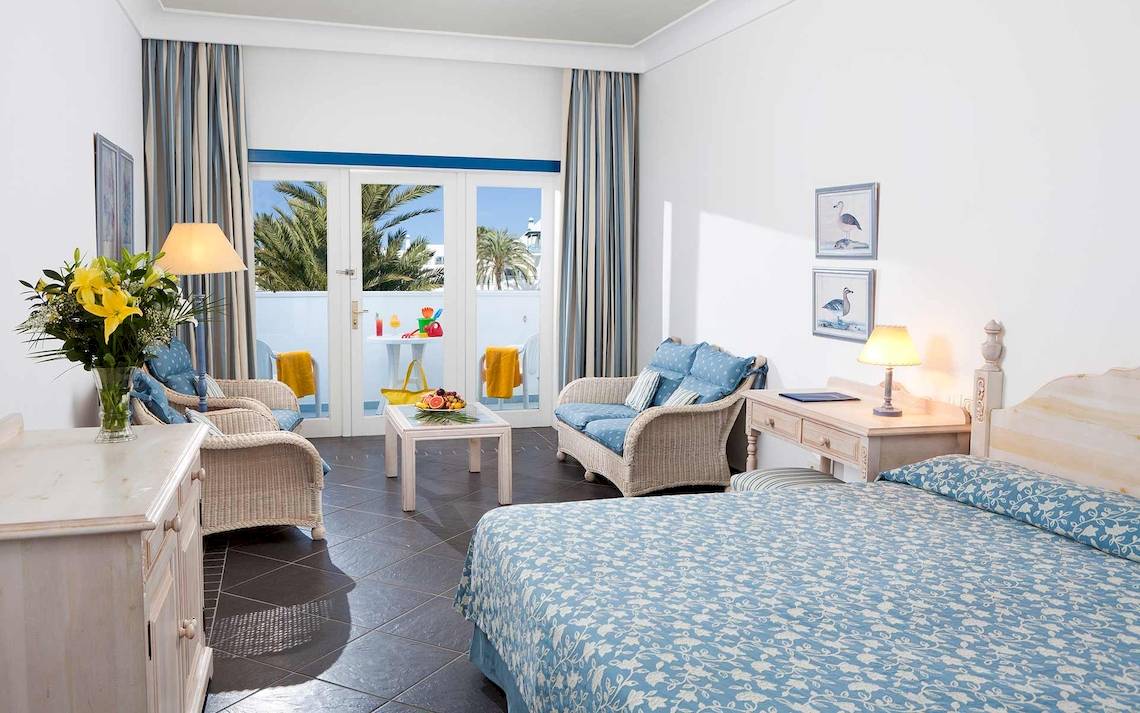 Innenansicht eines Schlafzimmers im Seaside Los Jameos Hotel mit Blick auf einen Balkon.