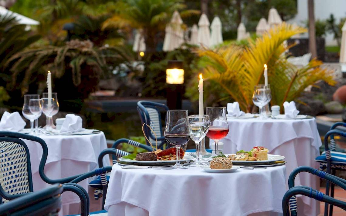 Restauranttisch im Freien im Seaside Los Jameos Hotel mit gedeckten Tischen und Gerichten.