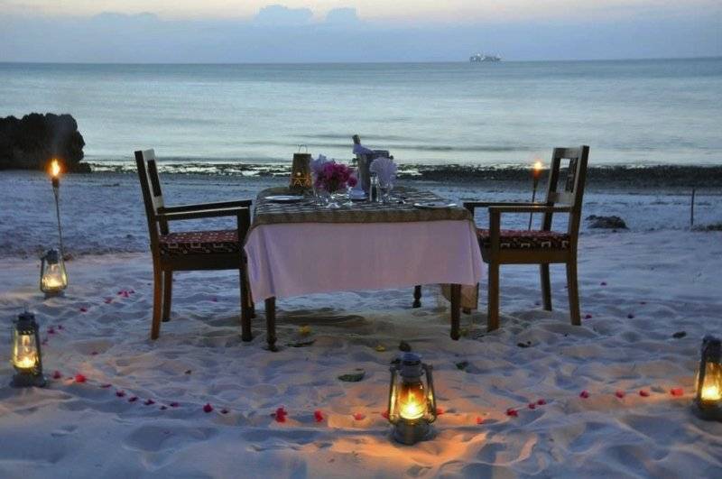 Ein romantisches Abendessen auf dem Strand im Zanzi Resort mit Kerzen und Rosenblättern.