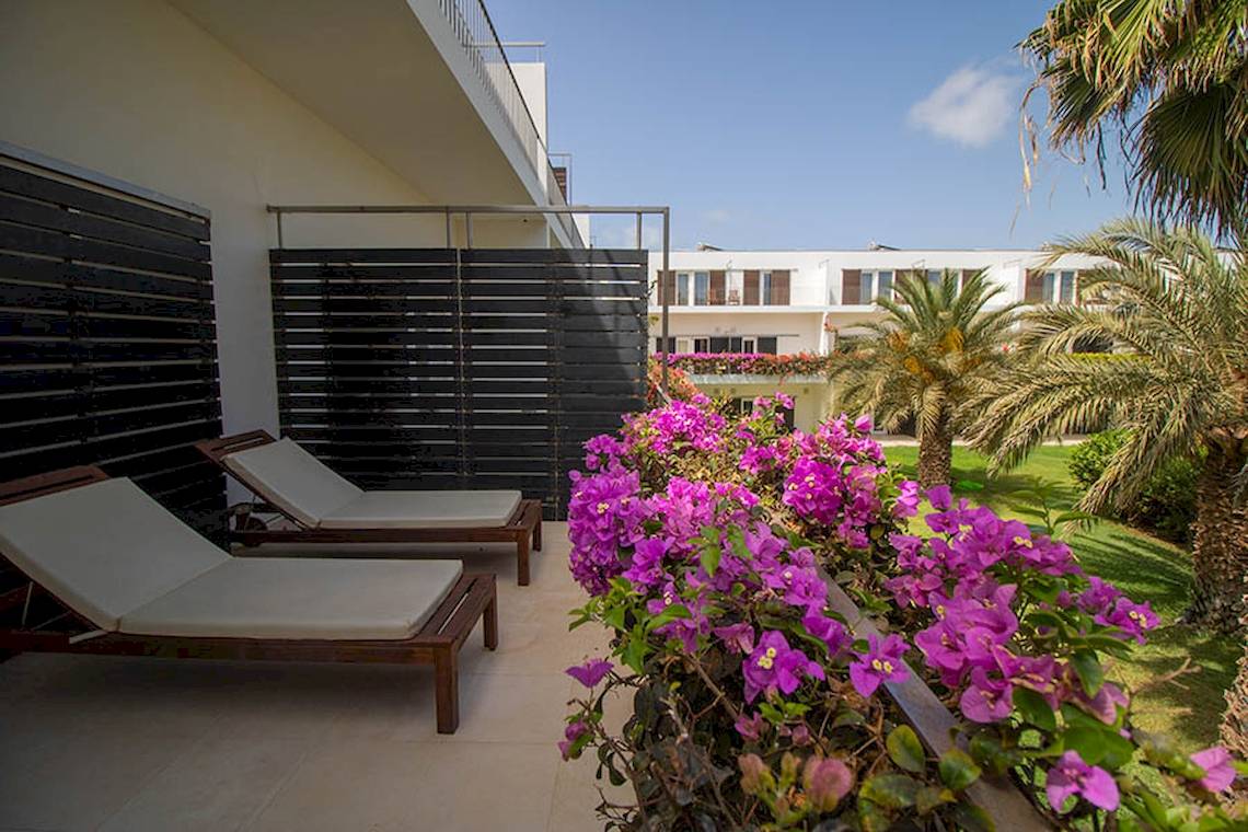 Terrasse im Dunas De Sal Hotel mit Loungeliegen und blühenden Bougainvillea-Pflanzen.