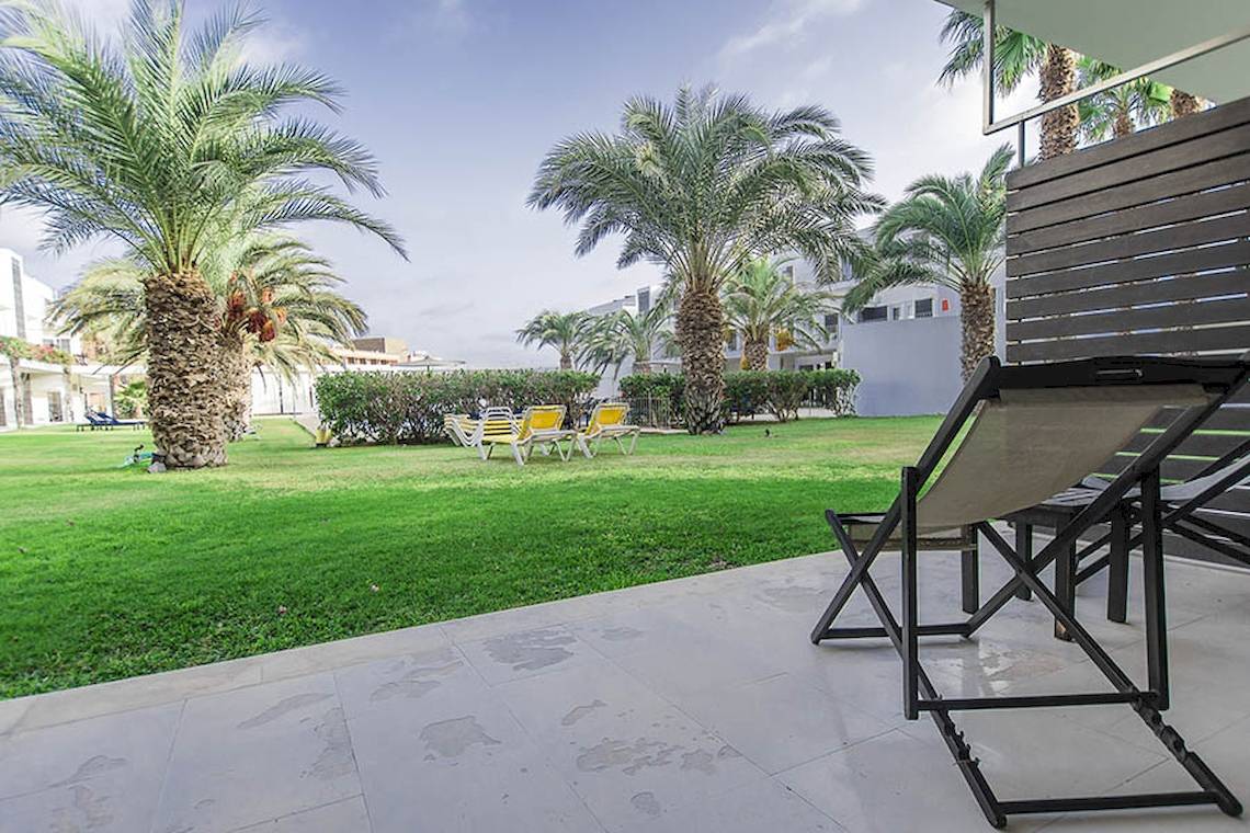 Gartenbereich des Dunas De Sal Hotels mit Palmen, Liegen und einem Tisch.