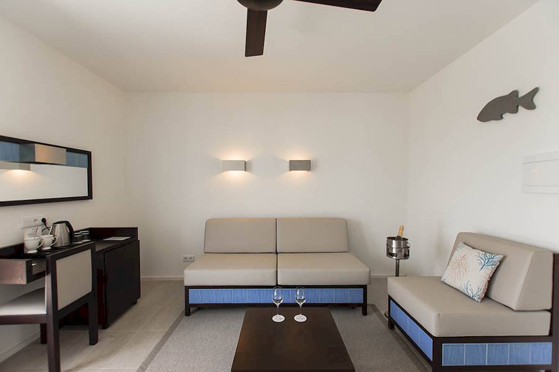 Wohnbereich im Dunas De Sal Hotel mit Sofa, Couch, Tisch und Schreibtisch.