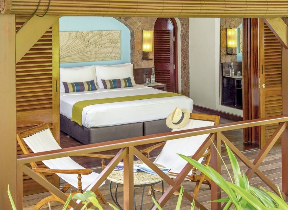 Schlafzimmer im Paradise Sun Hotel mit Zugang zum Balkon, inklusive Bett, Nachttischen und Stühle.