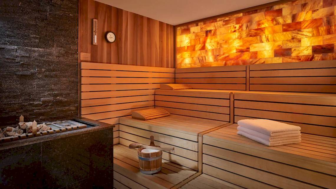 Innenansicht der Sauna im Grand Hyatt Abu Dhabi Hotel mit Holzbänken und orangefarbenen Wänden.