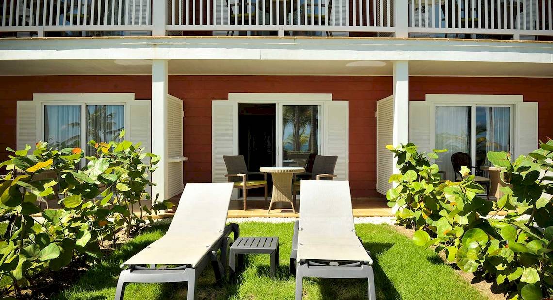 Terrasse des Barcelo Bavaro Beach Hotel mit zwei Lounge-Stuhlen und einem Tisch.