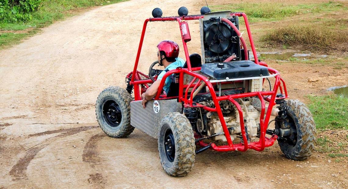 Mann im roten Helm fährt ein rotes Quad-Fahrzeug auf einem unbefestigten Weg im Barcelo Bavaro Beach Hotel.