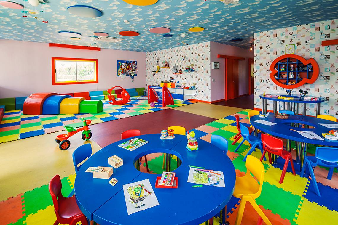 Kinderspielzimmer des Hotels Titanic Deluxe Lara mit bunten Teppichen, Spielzeug und Tischen.