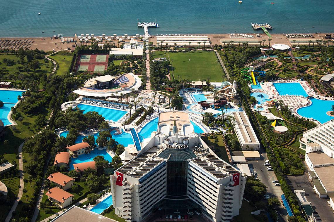 Luftaufnahme des Titanic Deluxe Lara Hotels mit Pools, Tennisplätzen und einem Meer im Hintergrund.