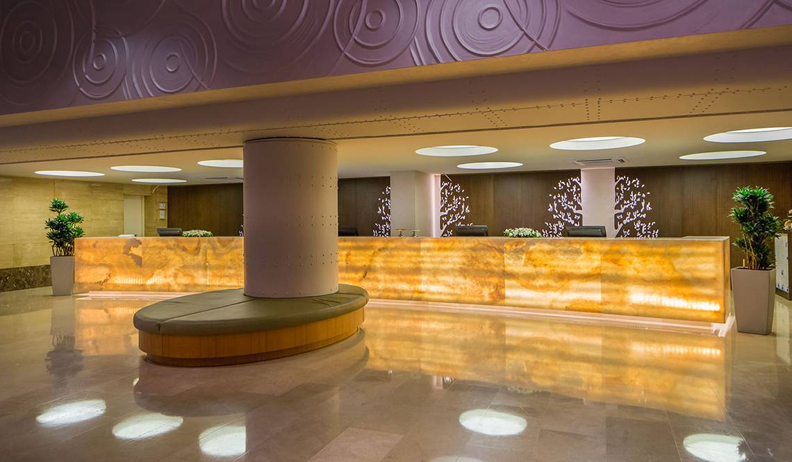Empfangsbereich des Titanic Deluxe Lara Hotels mit einem großen Empfangstisch, Säulen und Pflanzen.