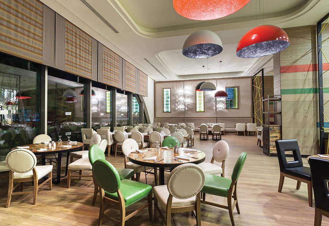 Innenbereich des Titanic Deluxe Lara Hotel Restaurants mit Holzboden, bunten Stühlen und Tischdecken.
