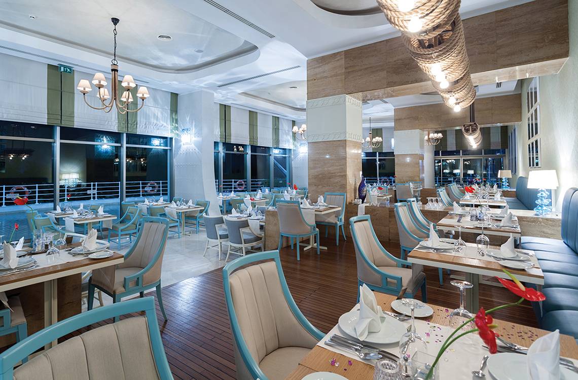 Innenansicht des Restaurants im Titanic Deluxe Lara Hotel mit blauen Stühlen und Tischen.