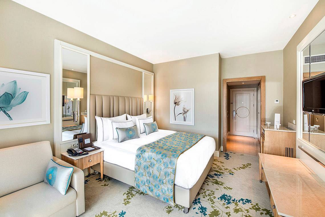 Elegantes Hotelzimmer im Titanic Deluxe Lara mit großem Bett und modernen Möbeln.
