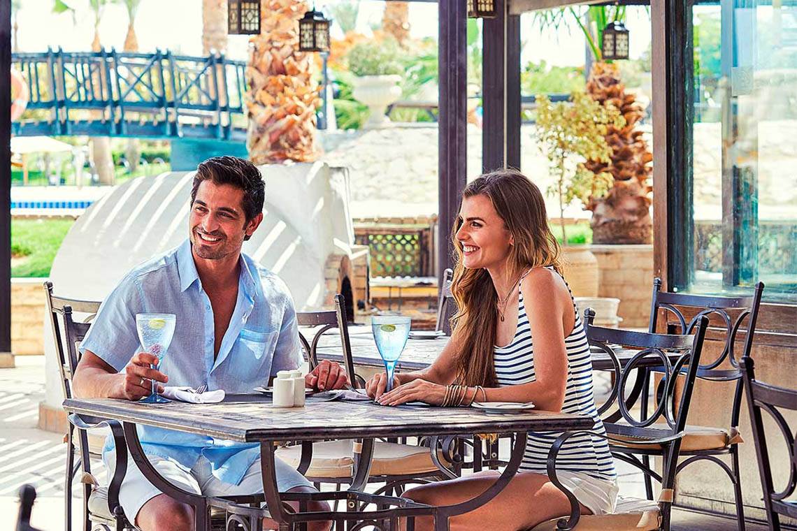 Paar im Hotelrestaurant beim Essen mit Blick auf den Pool