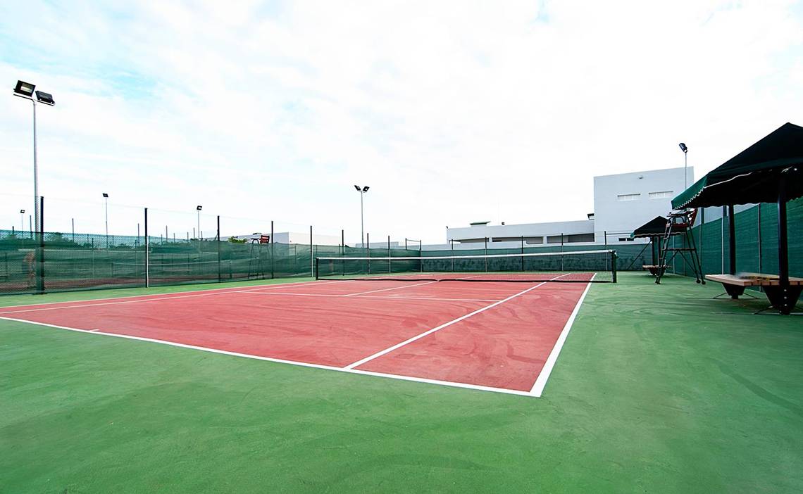 Ein leerer Tennisplatz im Freien mit grünem Boden und roten Markierungen.