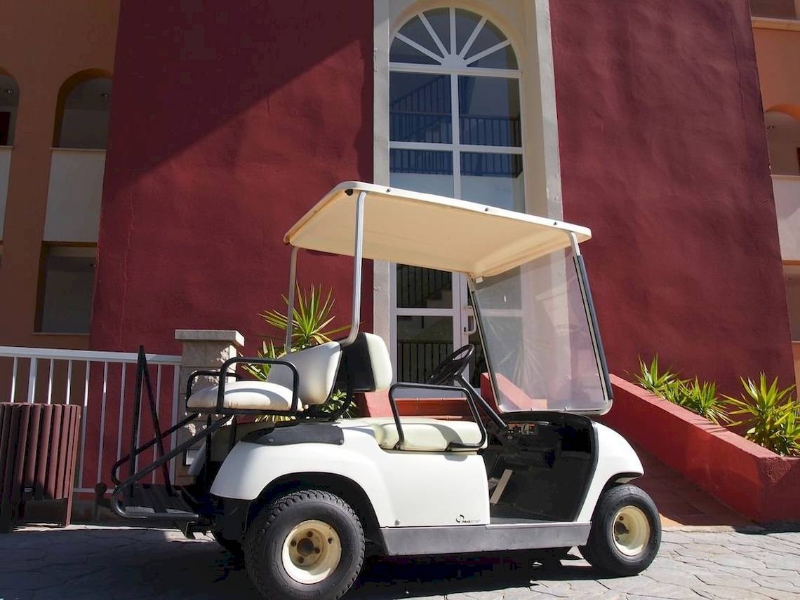 Ein weißer Golfwagen steht vor dem roten Gebäude des Hotels Bordoy Don Antonio.