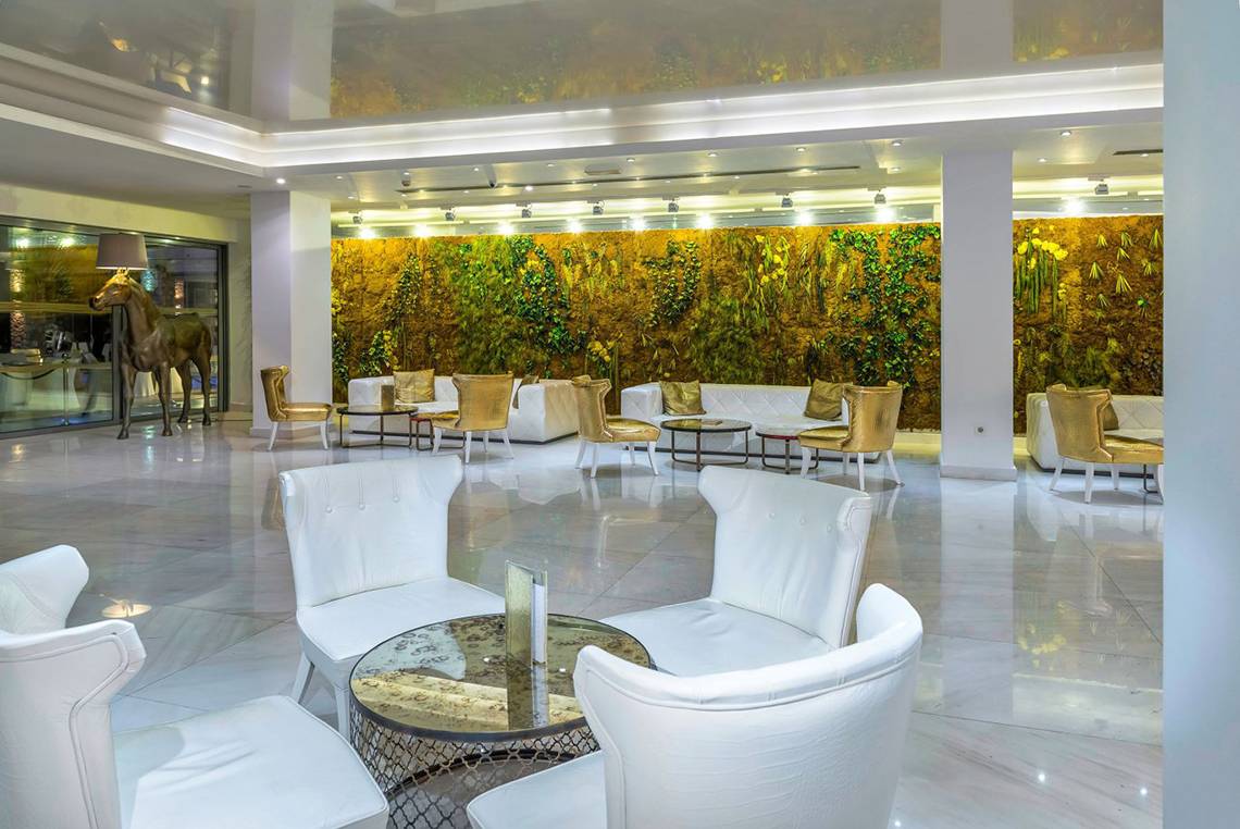 Lobby des Diamond Deluxe Hotels mit weißen Sofas und Tischen vor einer grünen Wand