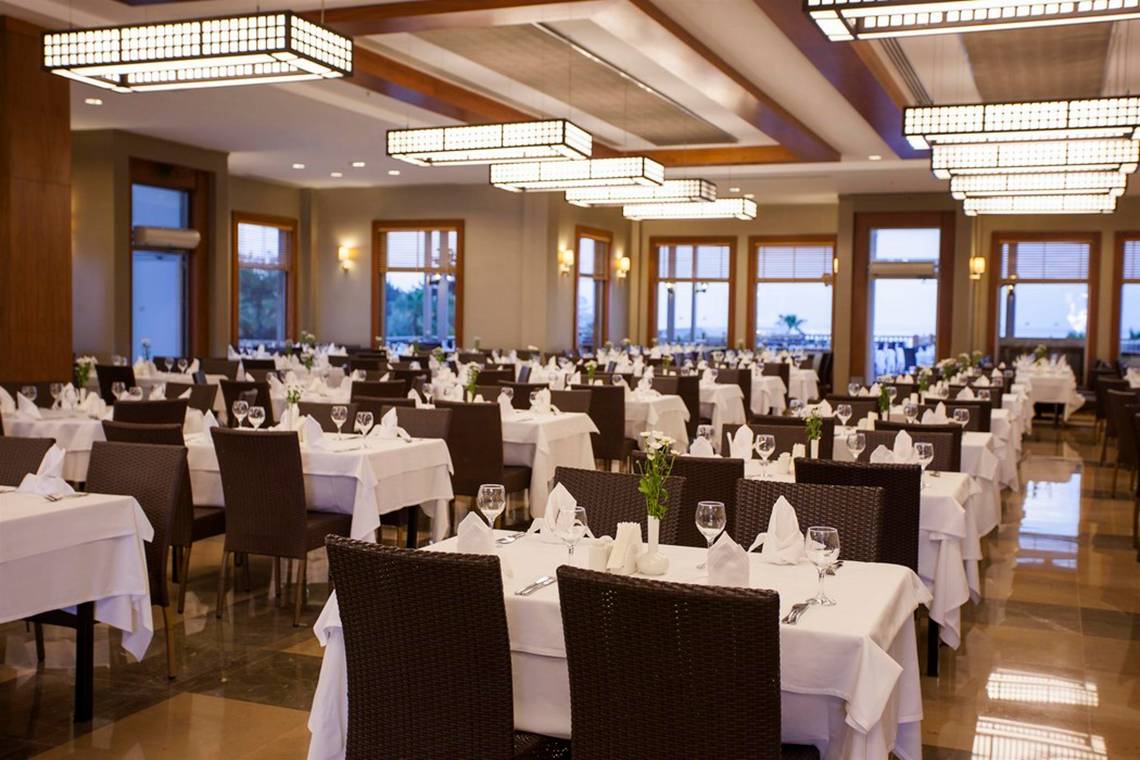 Innenansicht des Restaurants im Arcanus Side Resort Hotel mit gedeckten Tischen und modernen Deckenleuchten.