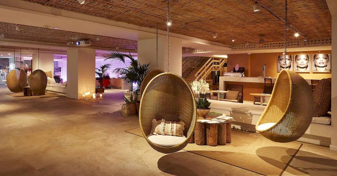 Lounge Bereich im ME Ibiza Hotel mit Hängesesseln, Pflanzen und einer Treppe.