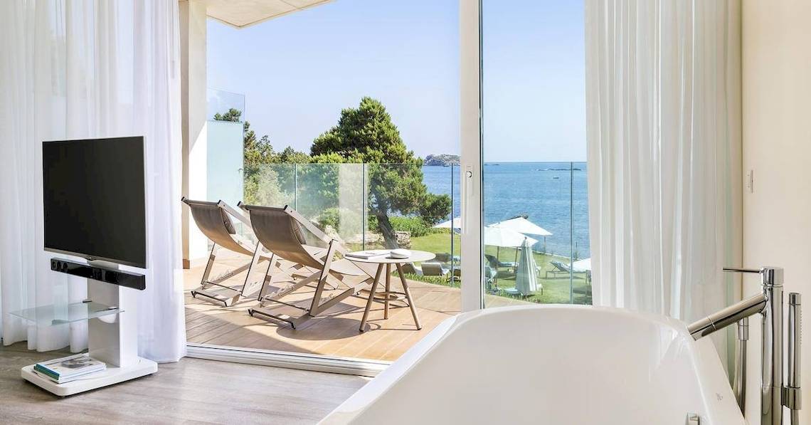 Innenansicht eines Zimmers im ME Ibiza Hotel mit Blick auf das Meer und Lounge-Stühlen.
