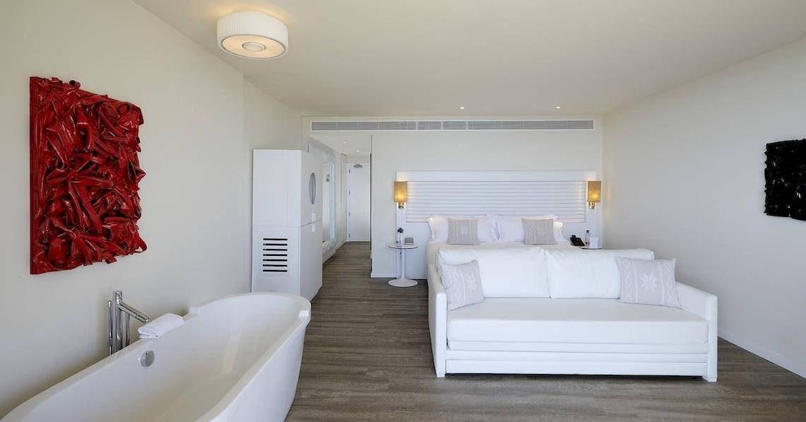 Innenansicht des Schlafzimmers im ME Ibiza Hotel mit Badewanne, Bett und Kunstwerk.