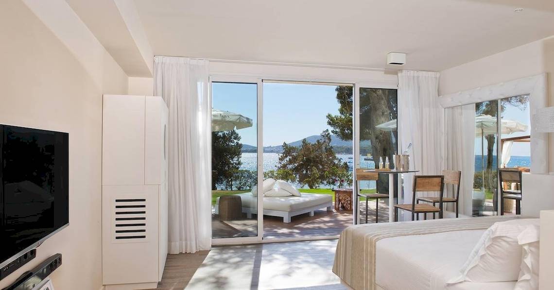 Innenansicht einer Suite im ME Ibiza Hotel mit Meerblick, Fernseher, Betten, Tisch und Stühlen.