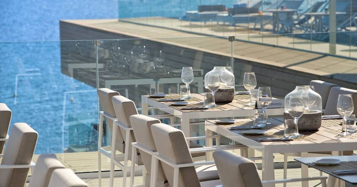 Außenterrasse des ME Ibiza Hotels mit Tisch und Gläsern vor Meerblick.
