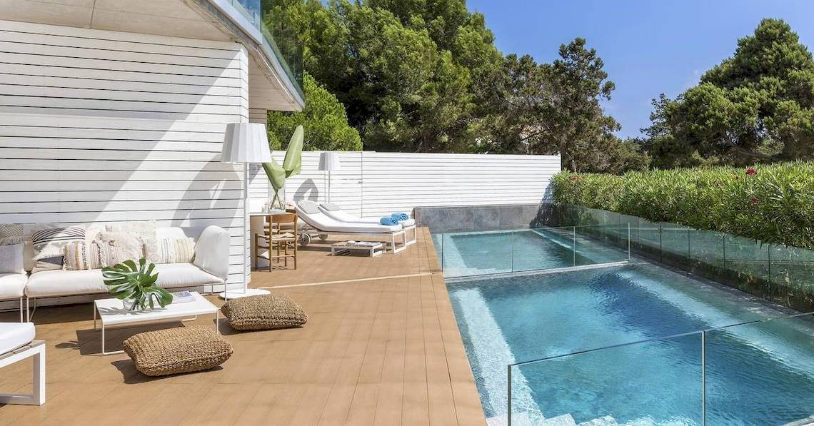 Terrasse des ME Ibiza Hotels mit Swimmingpool, weißen Möbeln und grünen Pflanzen.