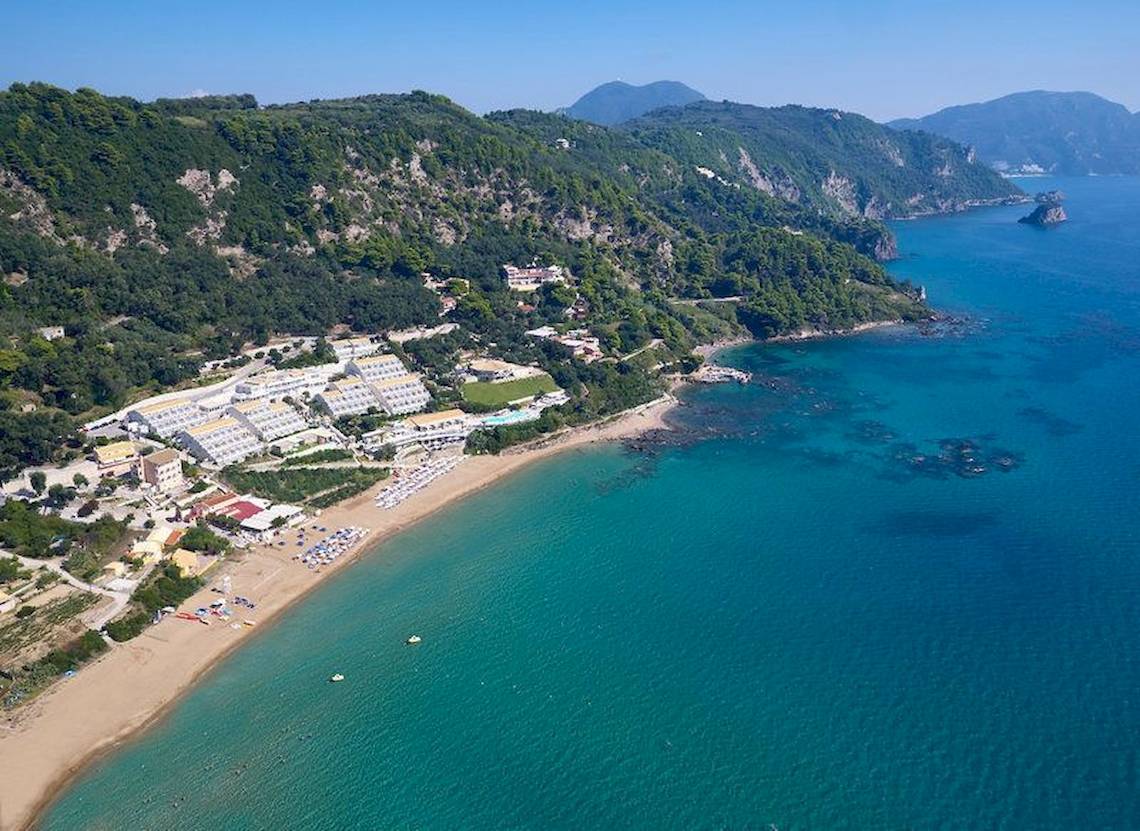Luftaufnahme des Pelekas Klosters mit Blick auf eine blaue Bucht und einen Sandstrand