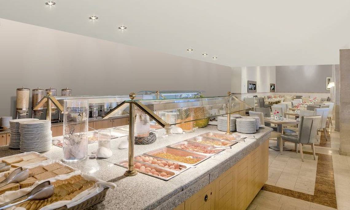 Frühstücksbuffet im Pelekas Monastery Hotel mit vielen Speisen und Geschirr.