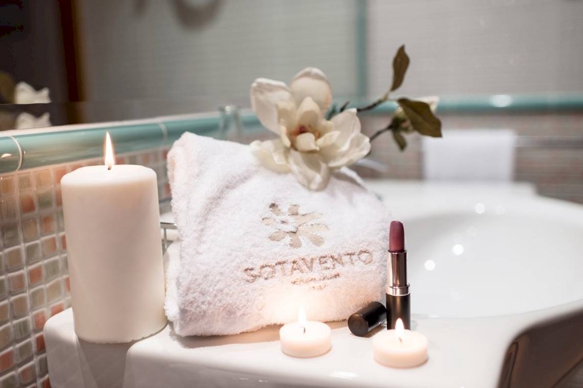 Badezimmer im Sotavento Beach Club mit einem Handtuch, Blumen, Kerzen und Kosmetik