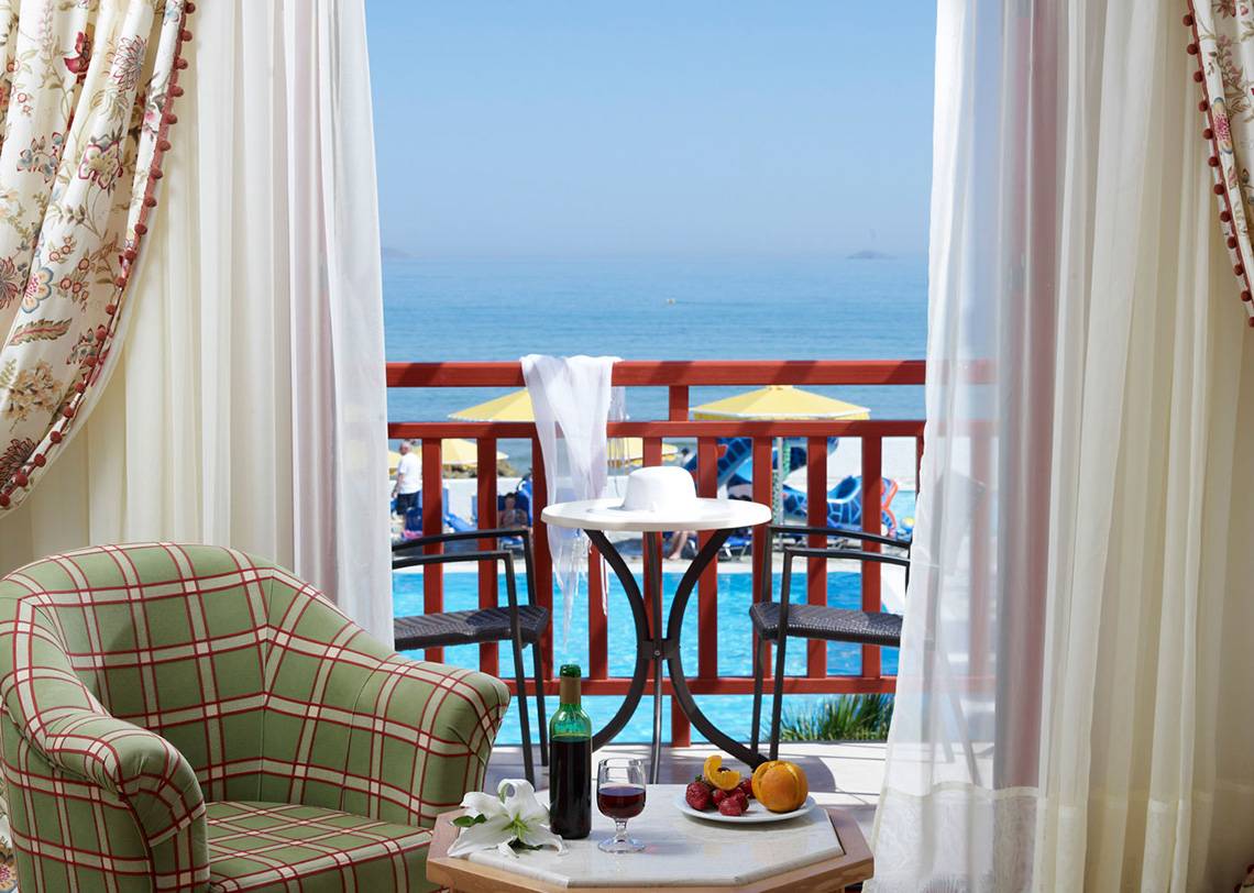 Blick vom Balkon des Mitsis Rinela Beach Hotels auf den Pool und das Meer.