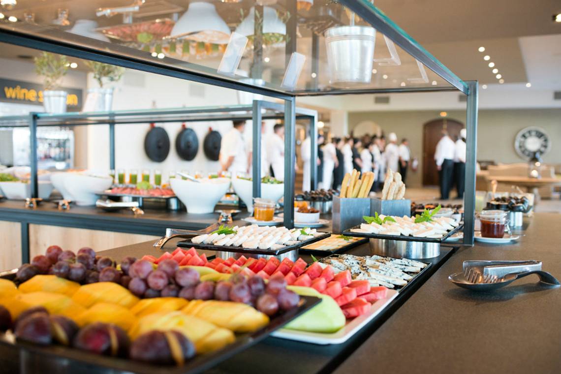 Frühstücksbuffet im Minos Palace Hotel mit verschiedenen Obst- und Käseplatten.