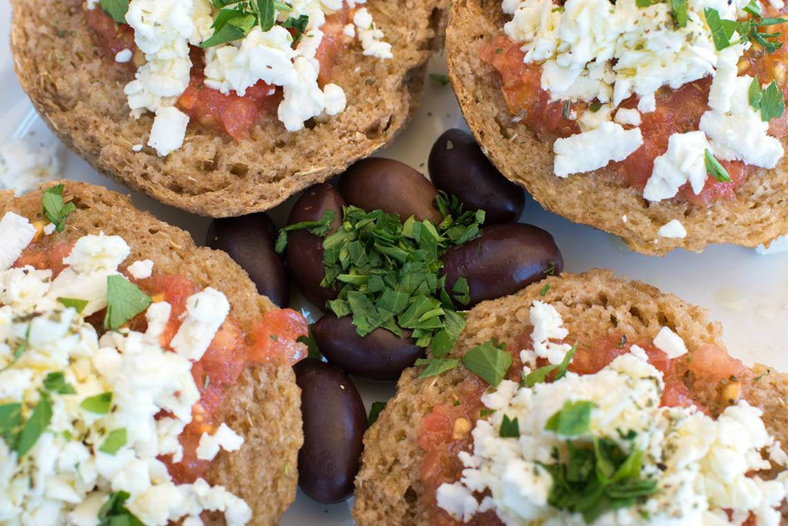 Griechisches Brot mit Tomaten und Fetakäse, serviert mit Oliven und Kräutern.